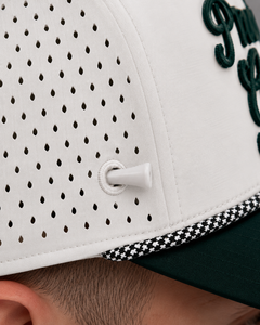 Close-up of tee holder on a white baseball cap with green text and a black rope, worn by a person.